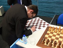 David Navara podepisuje šachovnici pro charitativní činnost